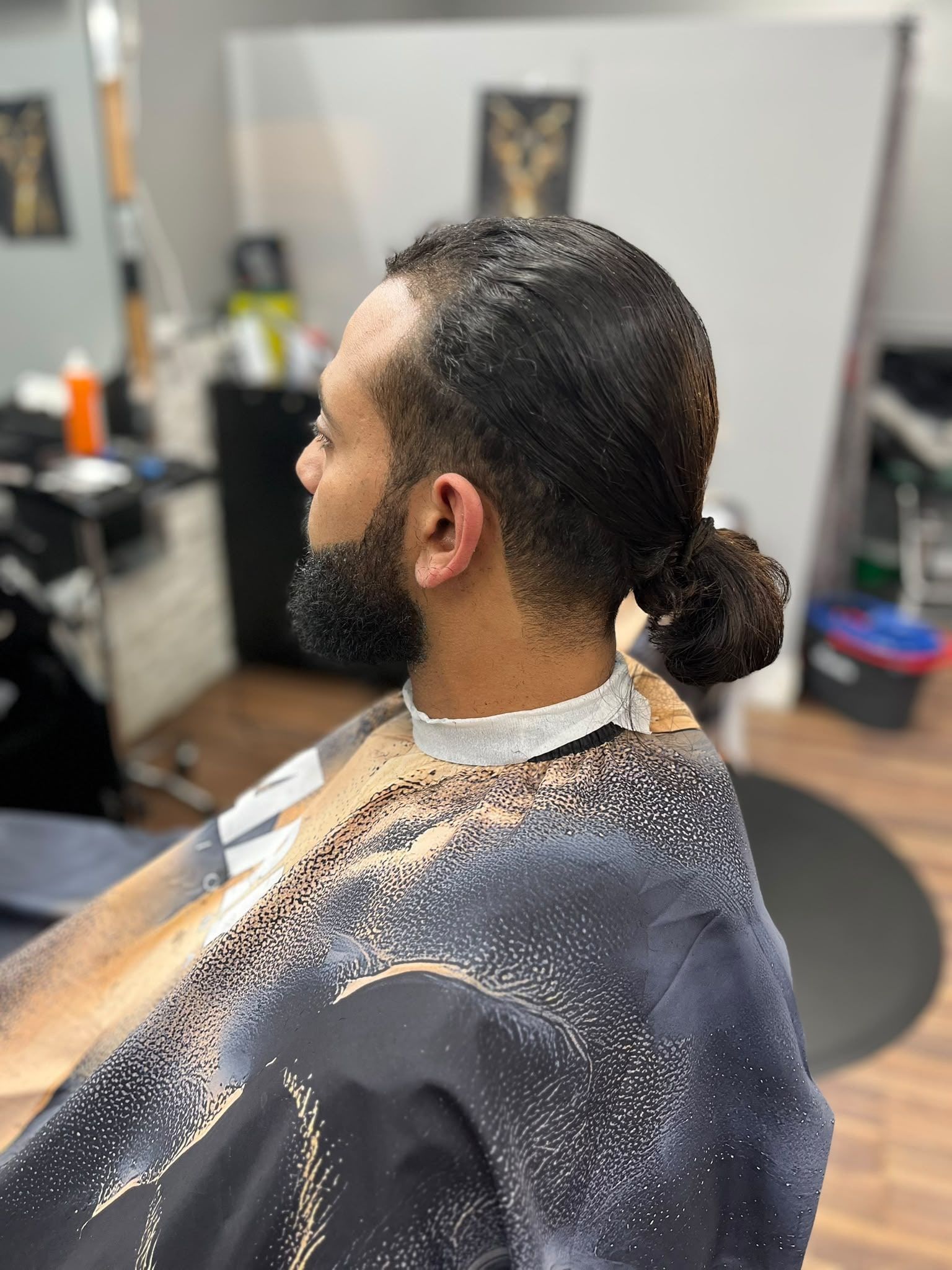 Man bun with a clean taper and a full beard